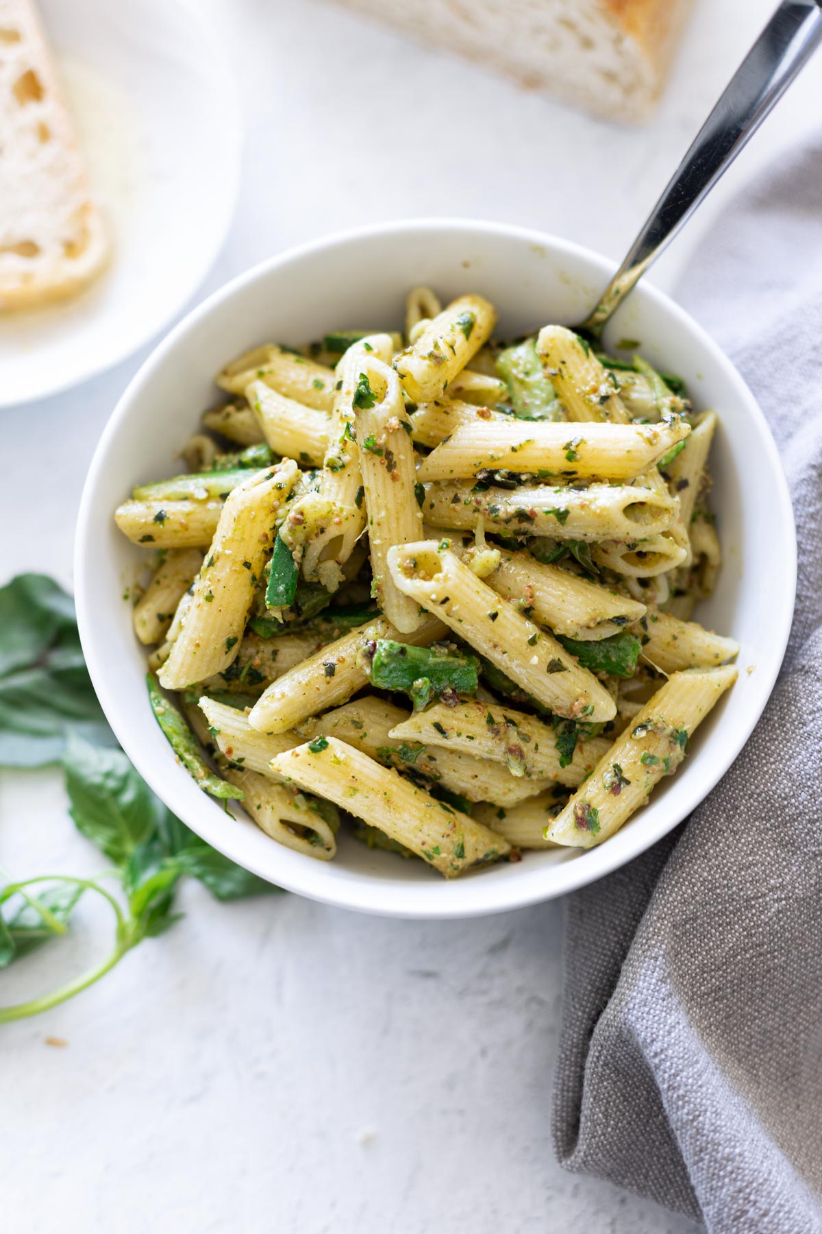 Bowl of pesto pasta topped with asparagus. 