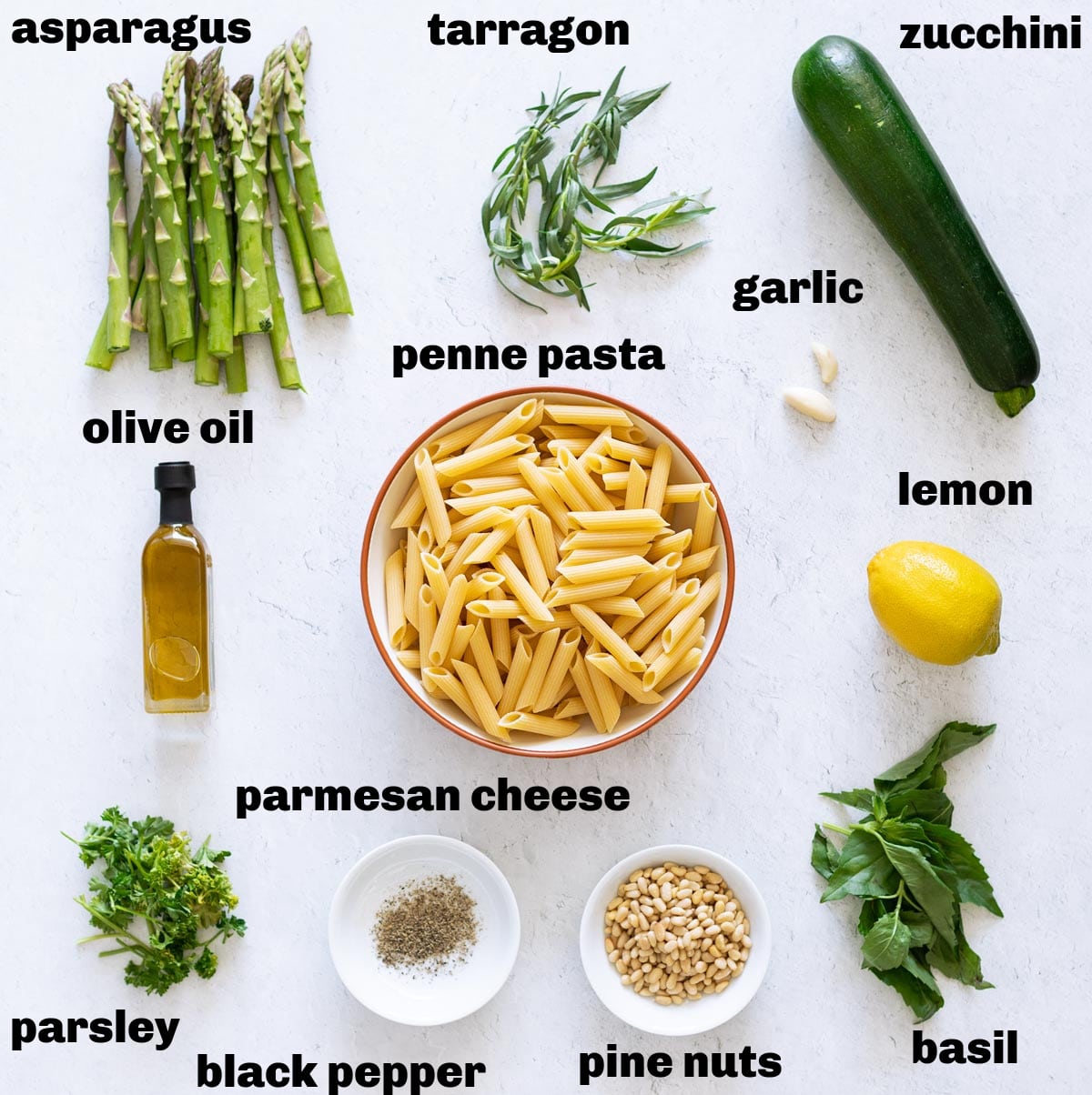 Fresh vegetables, pasta, and sauce ingredients on a counter to make creamy pesto pasta. 