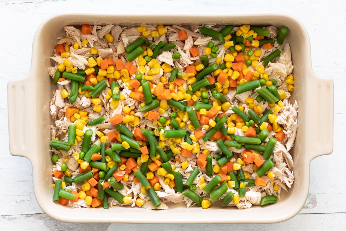 Pyrex pan of shredded chicken and mixed vegetables combined.