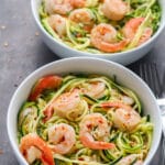 Two bowl filled with zucchini noodles topped with shrimp.