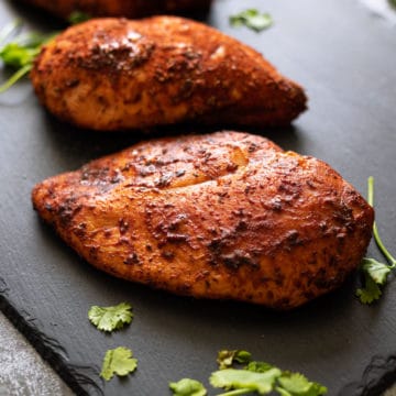 Closeup of smoked chicken breasts on a black slate