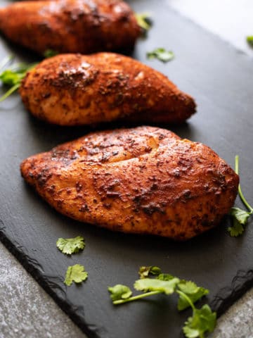 Closeup of smoked chicken breasts on a black slate