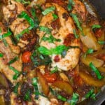 Skillet with four cooked chicken breast with peaches and cherry tomatoes