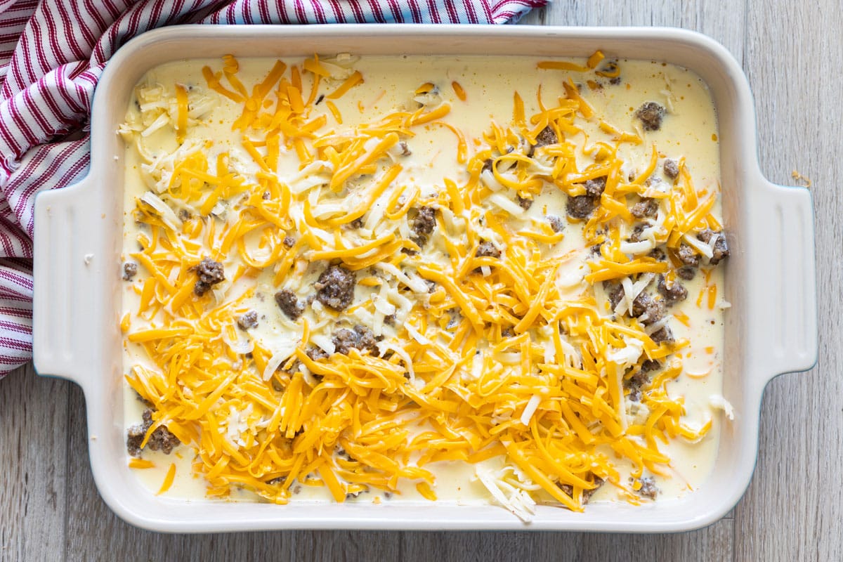 Raw breakfast casserole topped with cheese. 