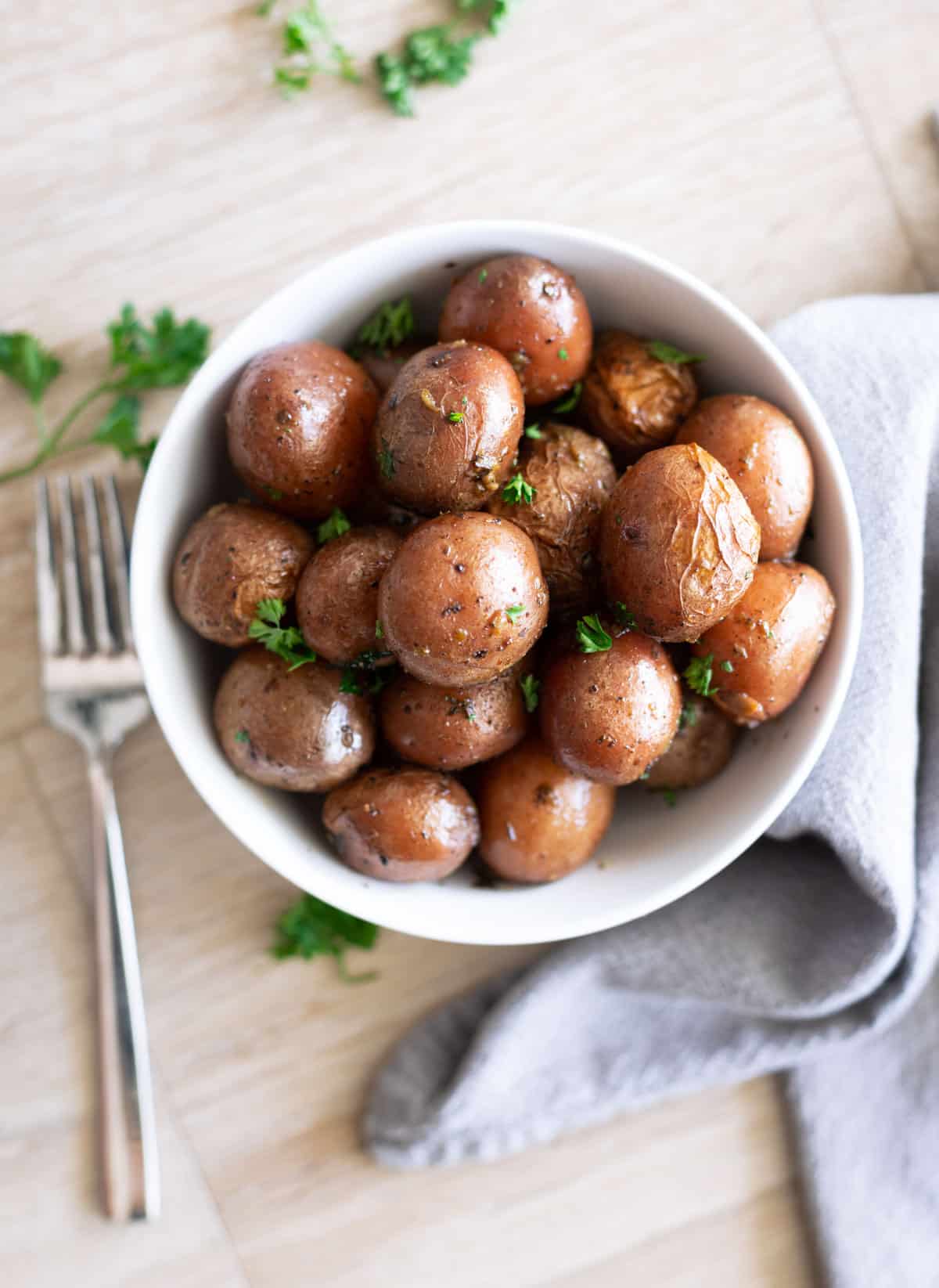 A bowl filled with slow-cooked baby potatoes topped with fresh parsley. 