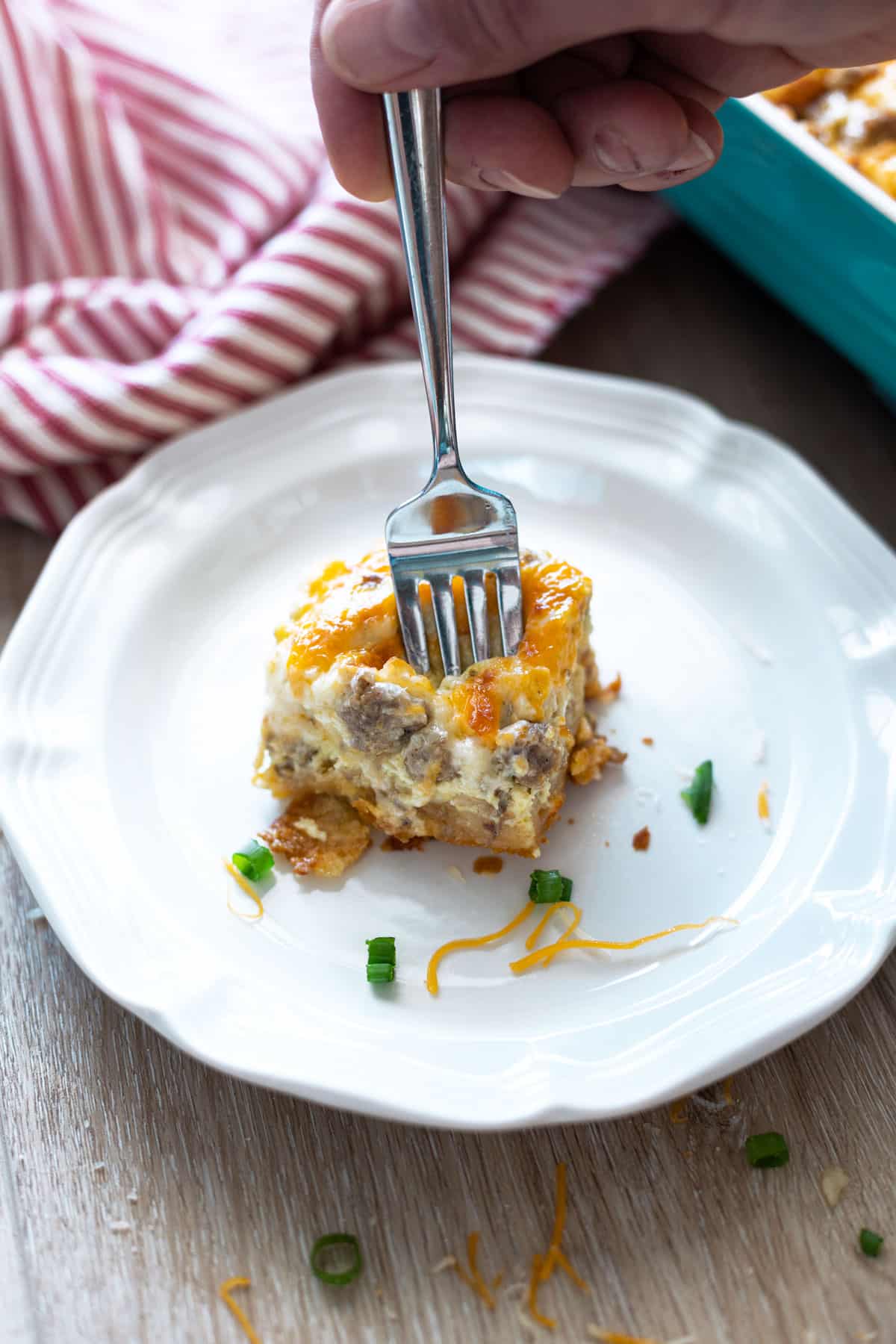 Piece of egg and sausage breakfast casserole on a plate with a fork. 