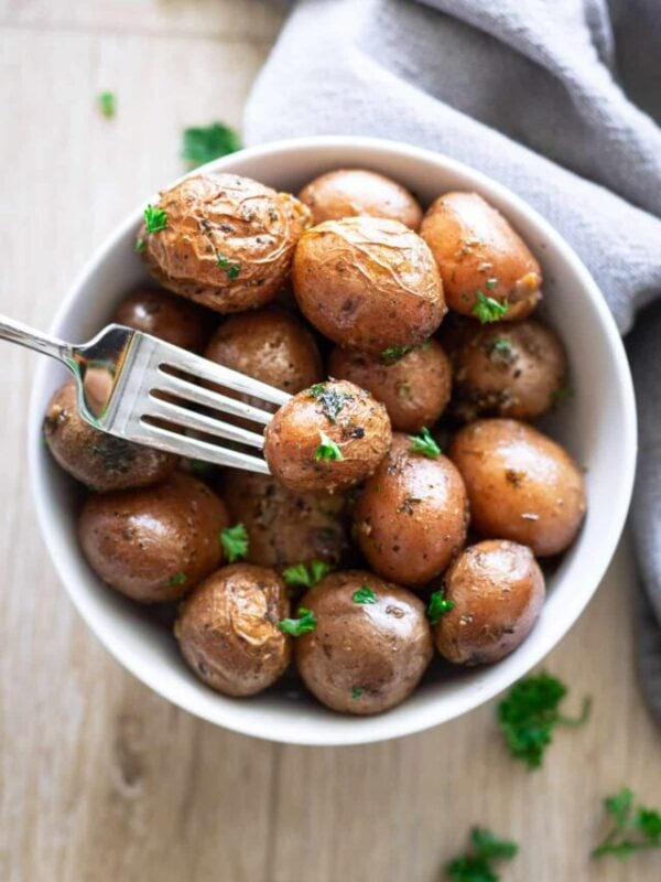 White bowl containing garlic herb potatoes.