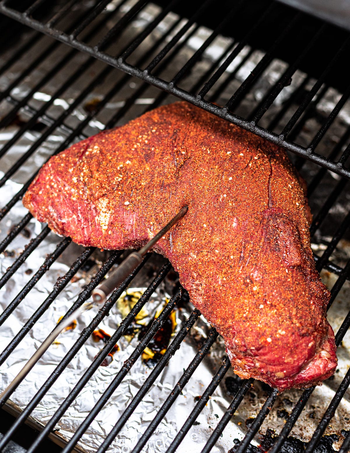 Steak on a pellet smoker with digital meat thermometer inserted. 