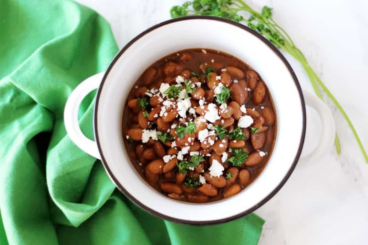 Bowl of pinto beans on table topped with feta cheese. 