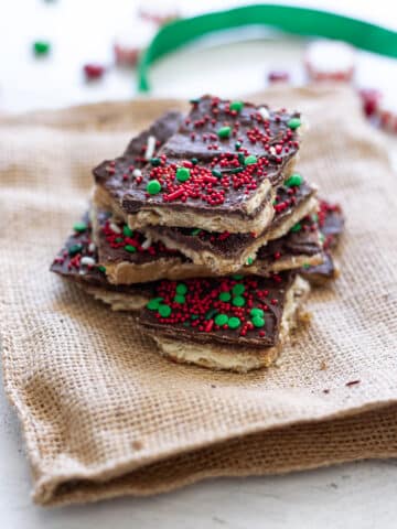 Stacked pieces of Christmas Crack Candy on a burlap cloth.