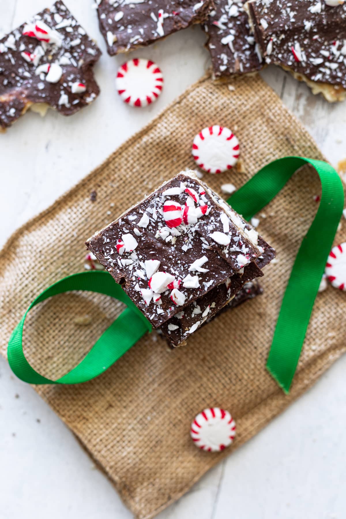 Peppermint topped Christmas crack being wrapped in a green ribbon. 