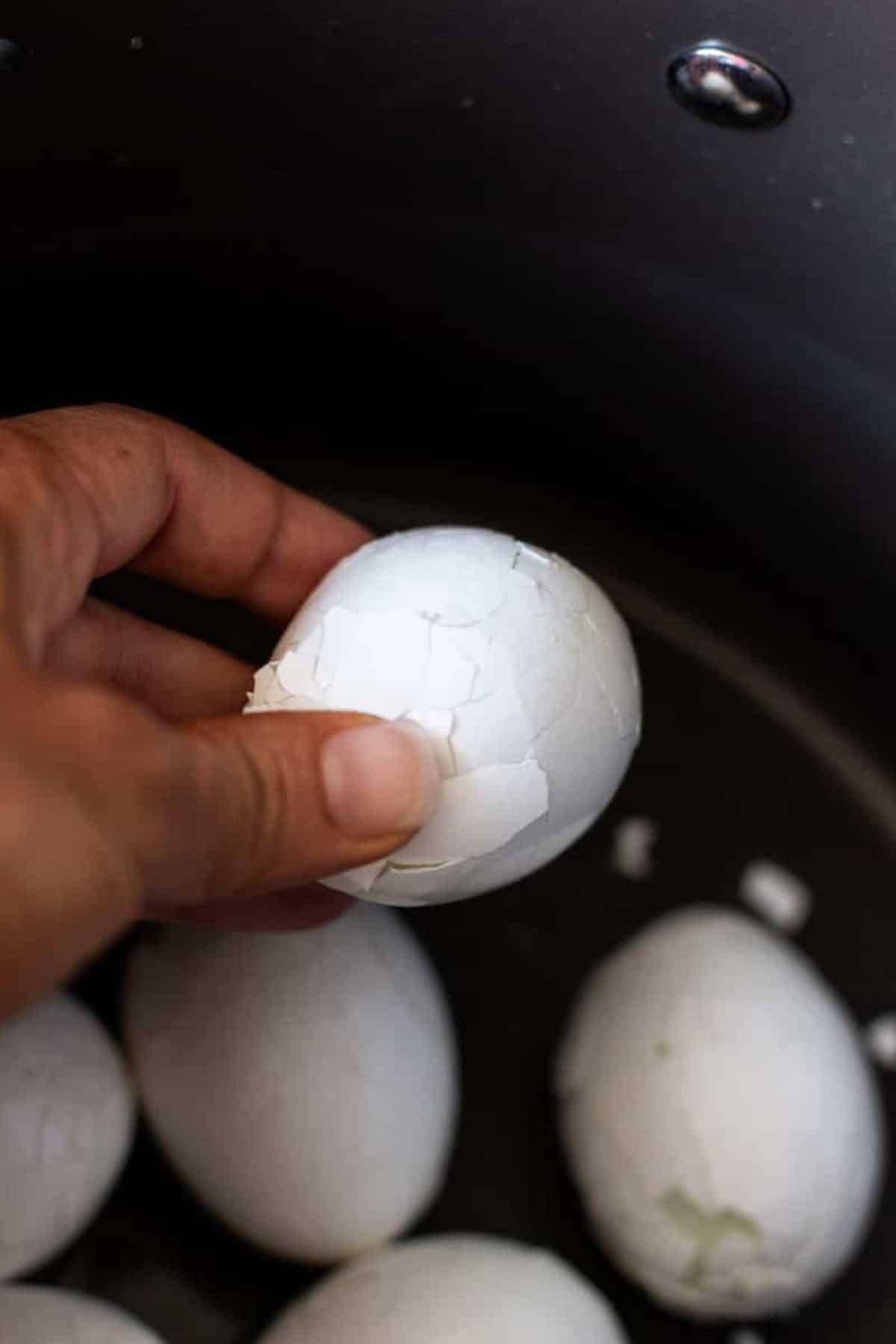 Person holding cracked hard boiled egg.