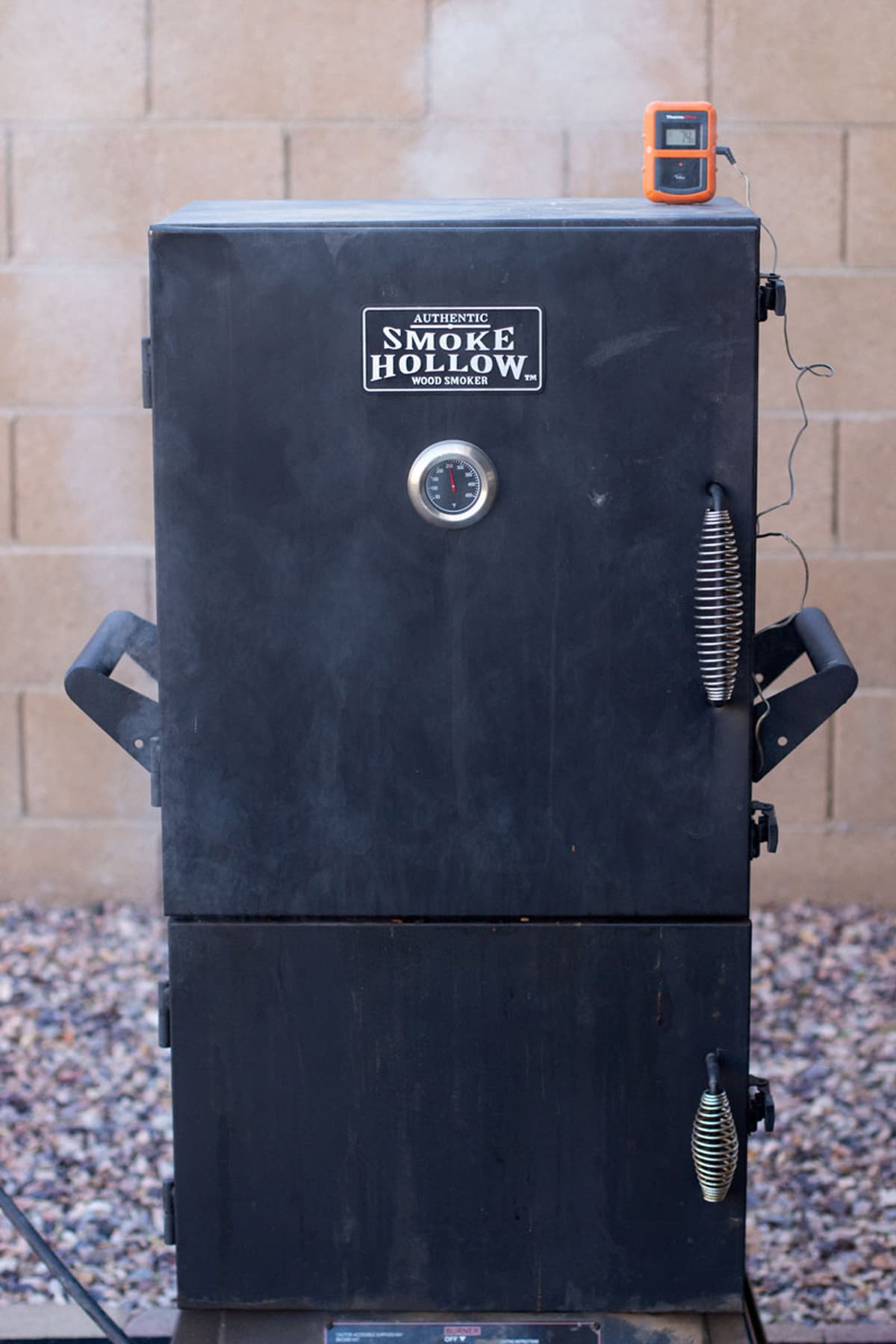 Smoke coming out of a smoker, temperature gauge on smoker.