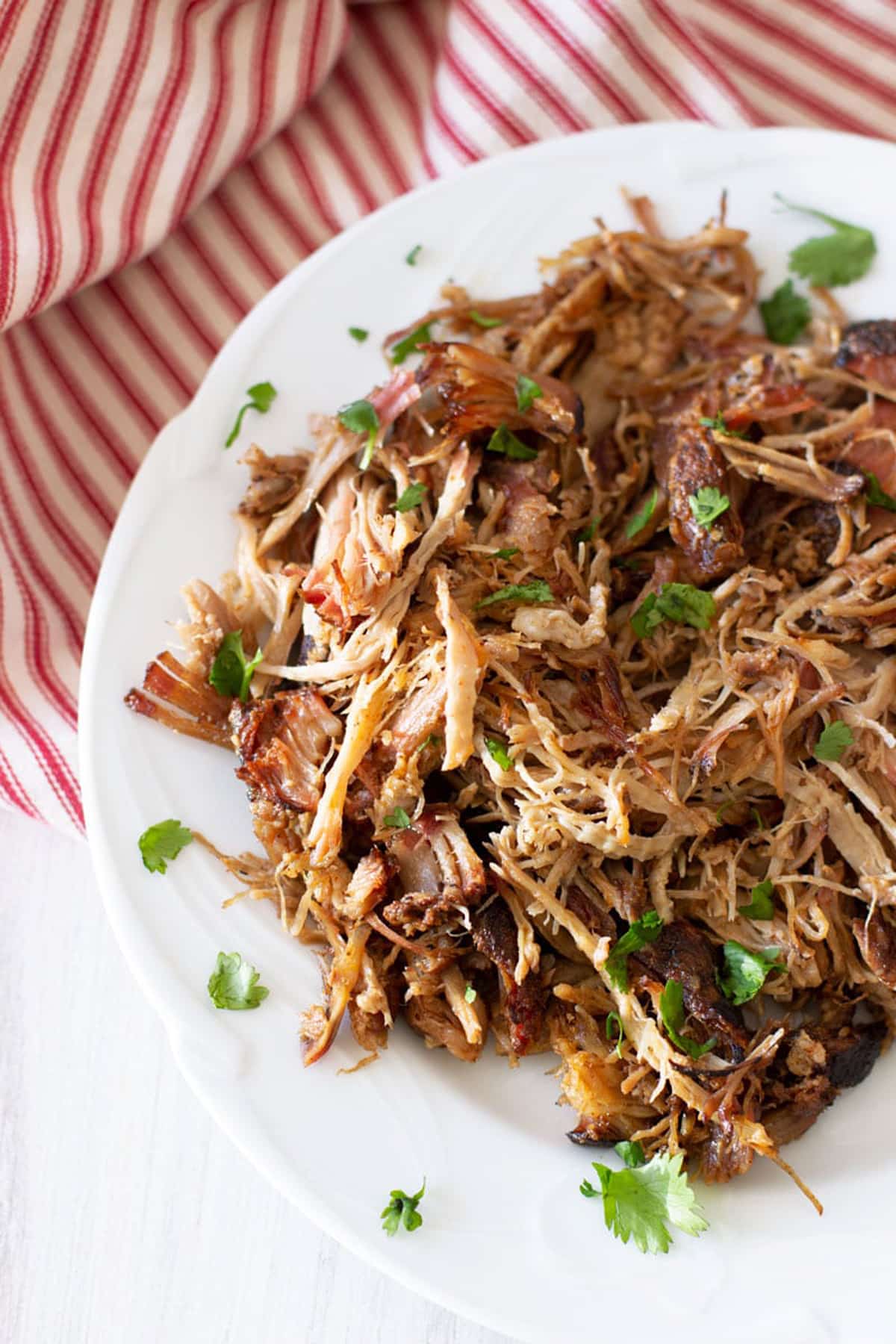 Plate of shredded pulled pork topped with fresh parsley. 