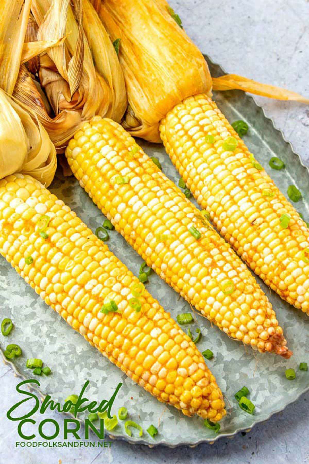 Three cobs of corn topped with butter and scallions. 