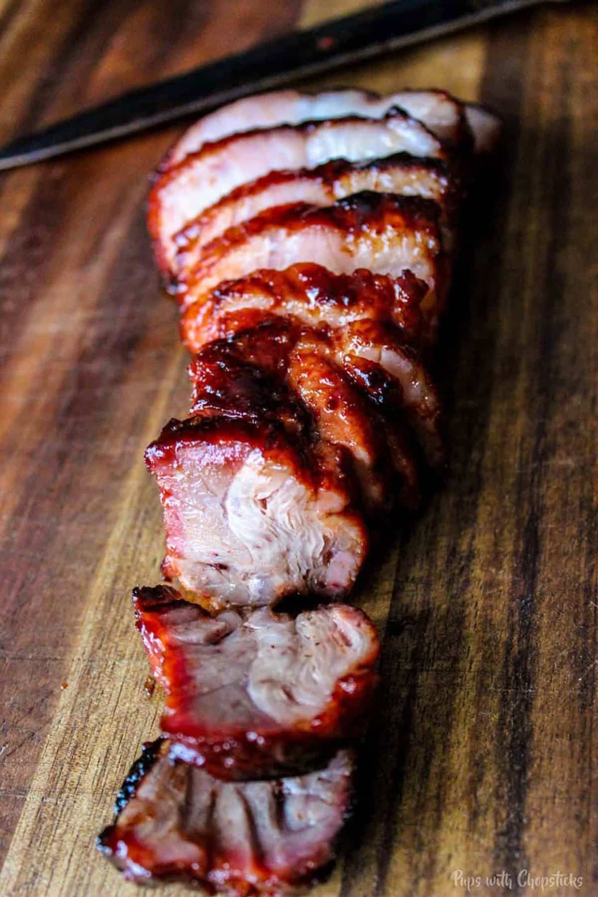 Sliced BBQ Chinese pork on a cutting board. 
