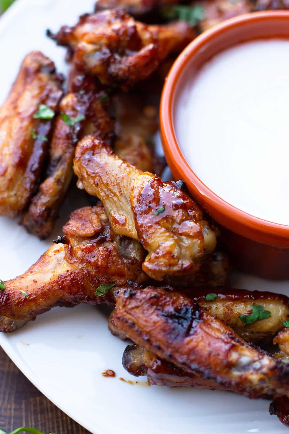 Barbecue chicken wings on a platter, side of ranch. 