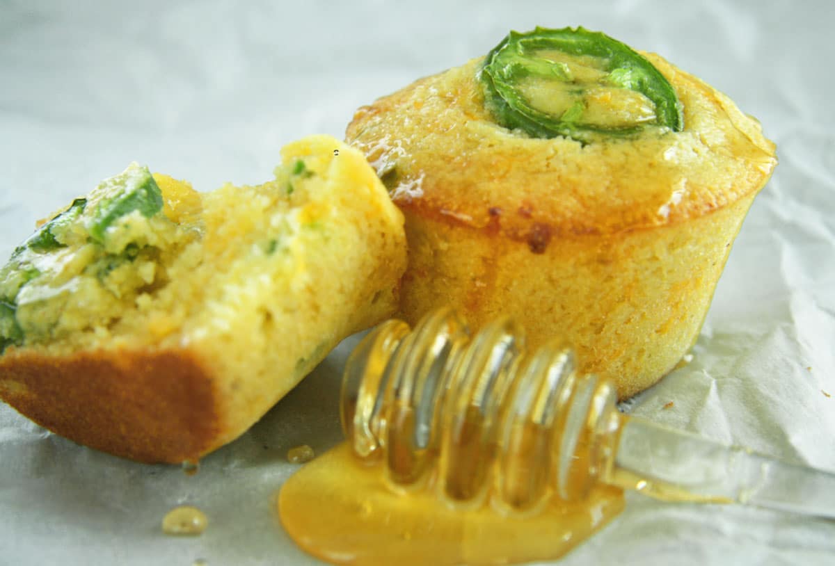 Honey jalapeno cornbread muffins with honey on table. 