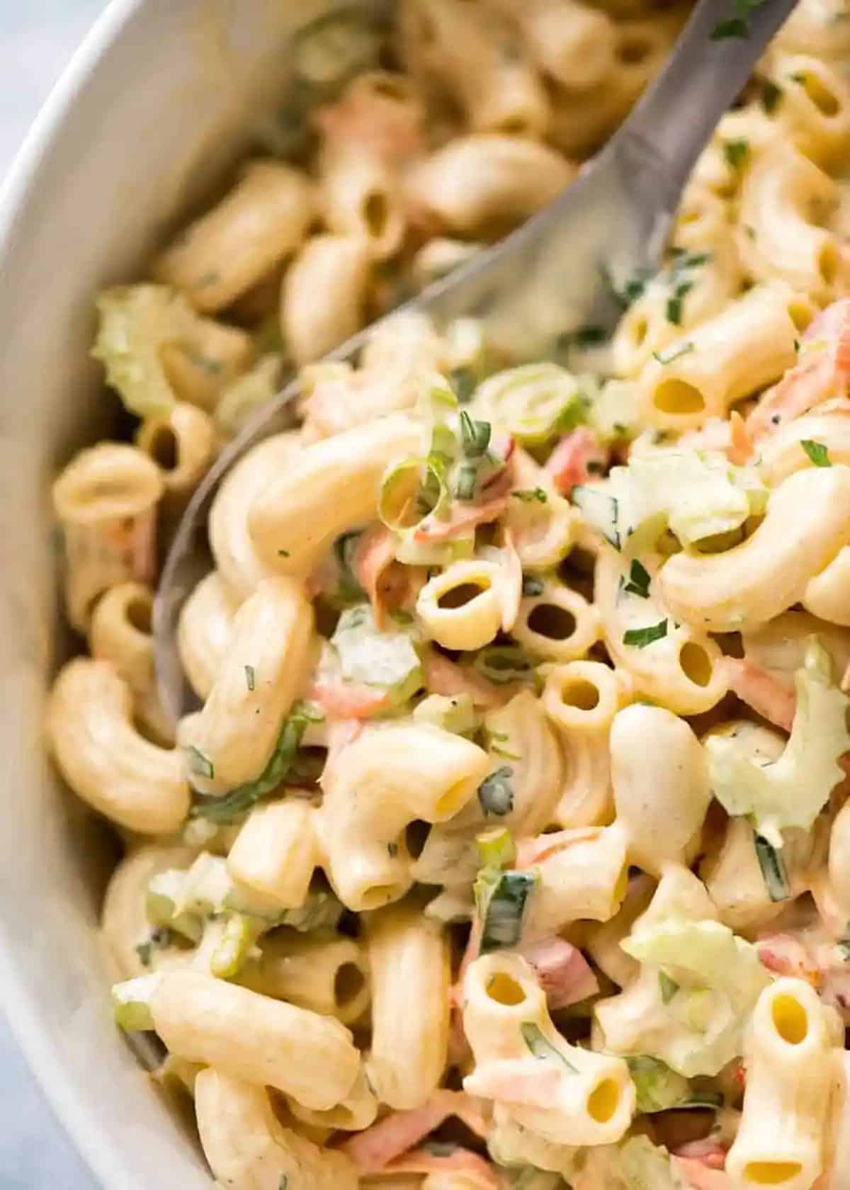 Close up of pasta salad in a bowl covered in dressing. 