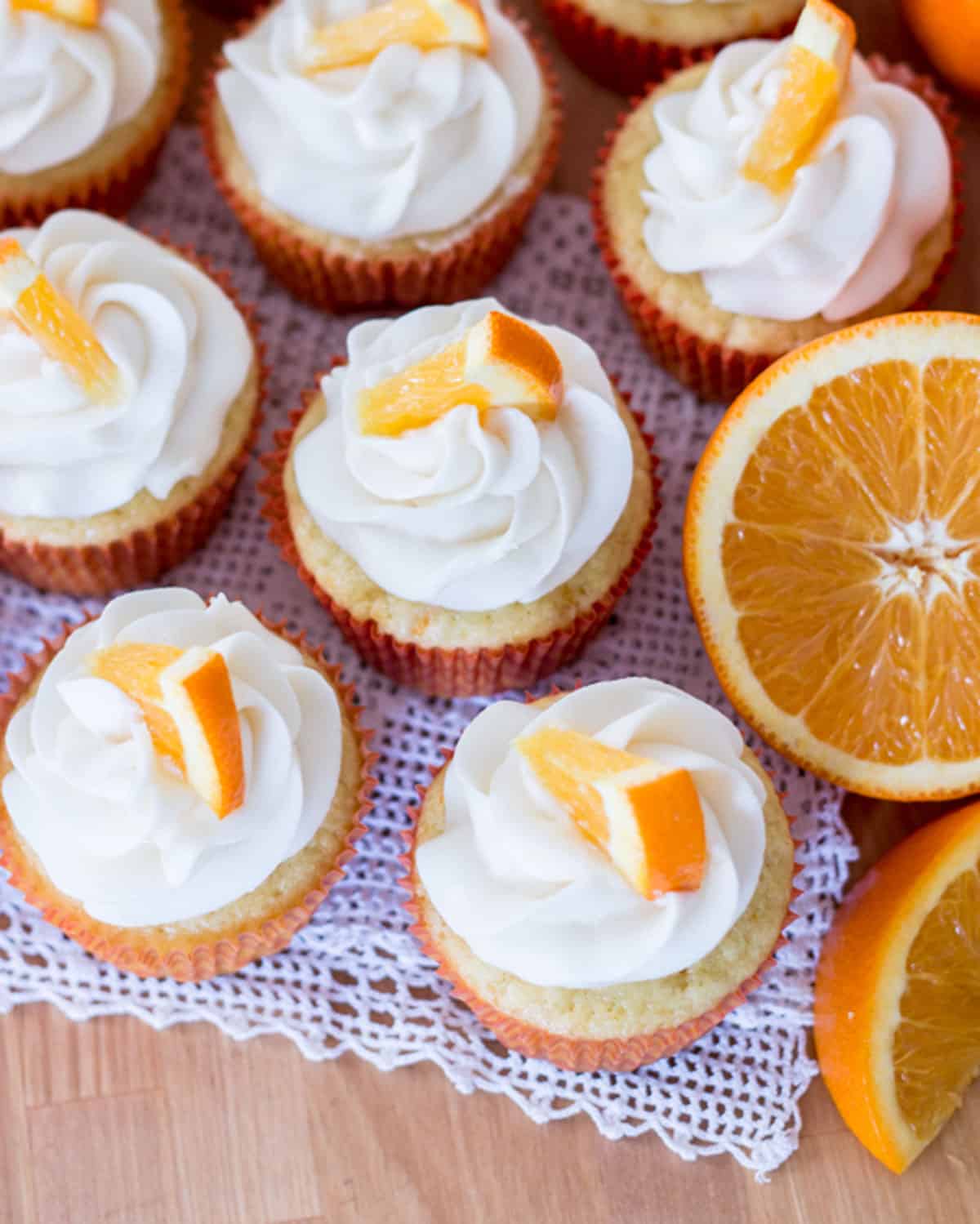 Orange cream filled cupcakes on a table.