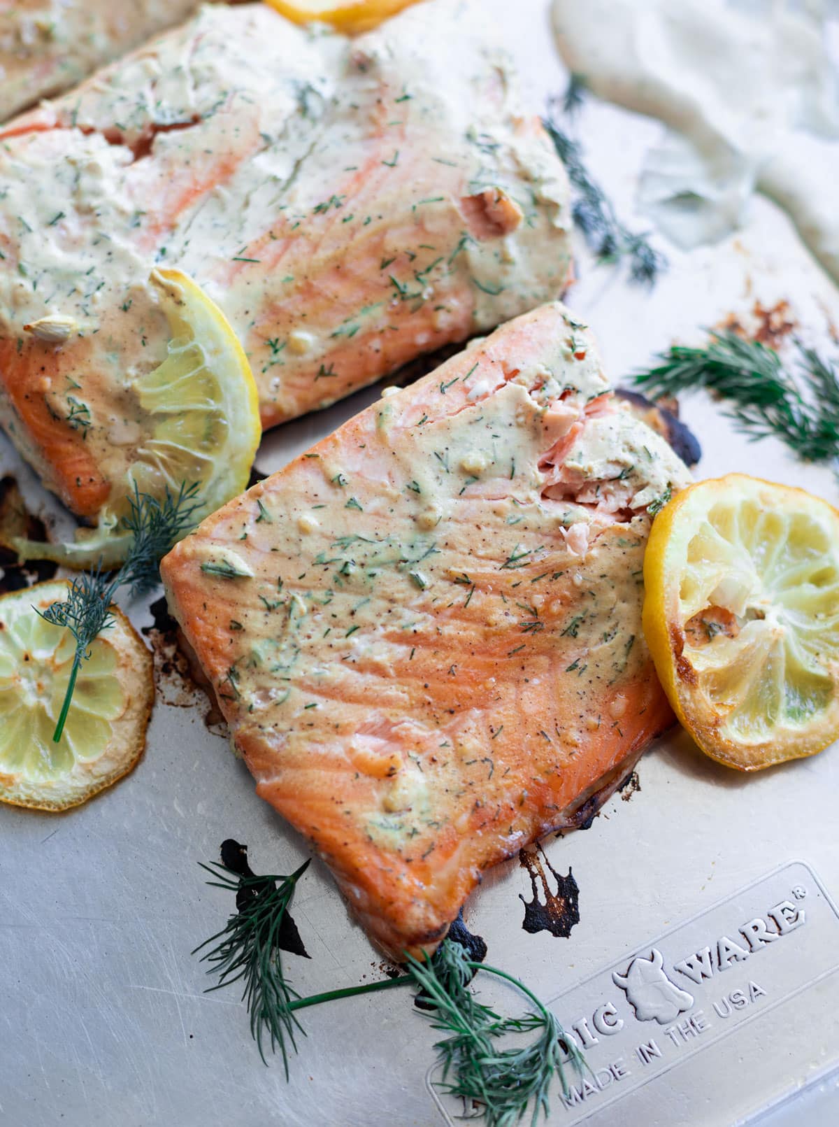 baked salmon with creamy dill sauce on a sheet pan with lemon slices