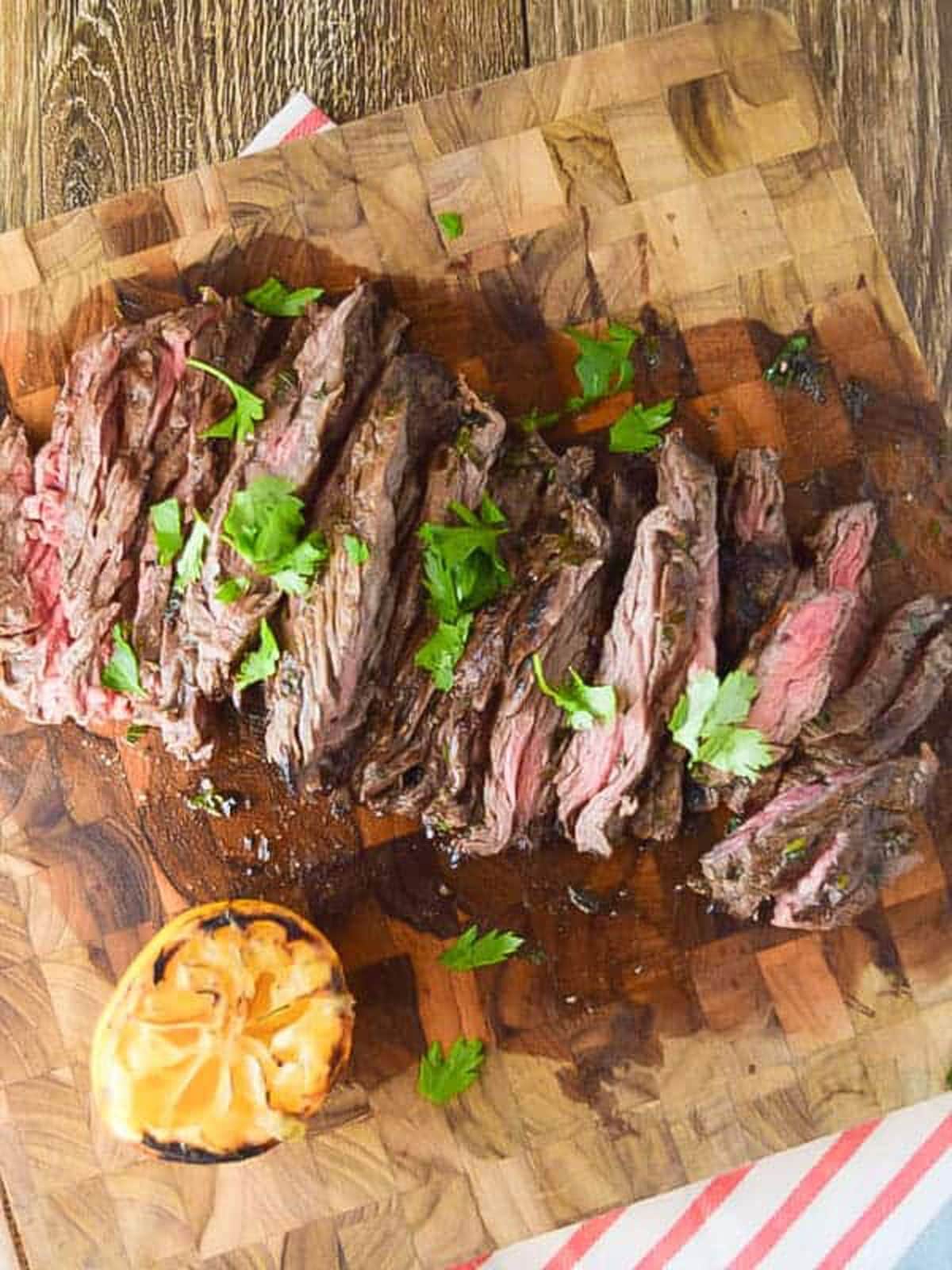 Slices skirt steak on a cutting board topped with cilatro. 