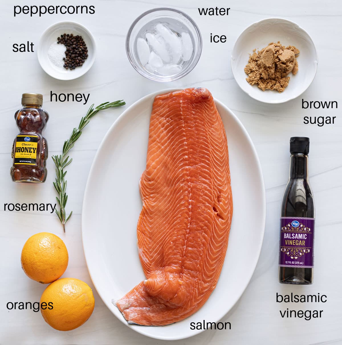 Salmon, oranges, rosemary, and other ingredients on a counter used to smoke fish. 