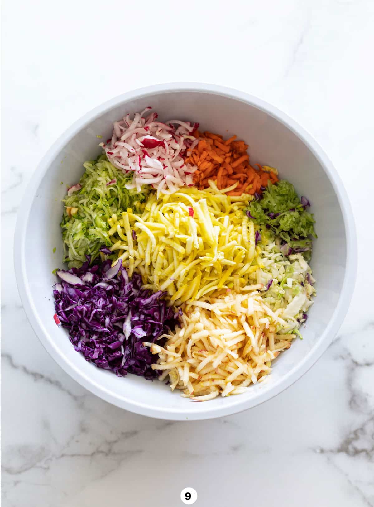 Bowl of shredded vegetables in a bowl on a counter to make coleslaw. 