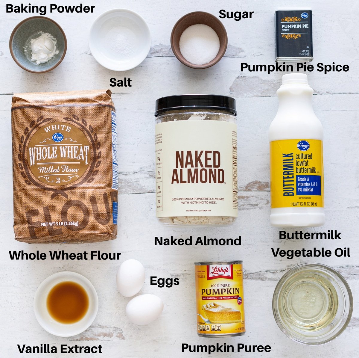 All of the ingredients needed to make pumpkin waffles: Baking powder, salt, sugar, pumpkin pie spice, whole wheat flour, naked almond, buttermilk, eggs, vanilla extract, and vegetable oil. 