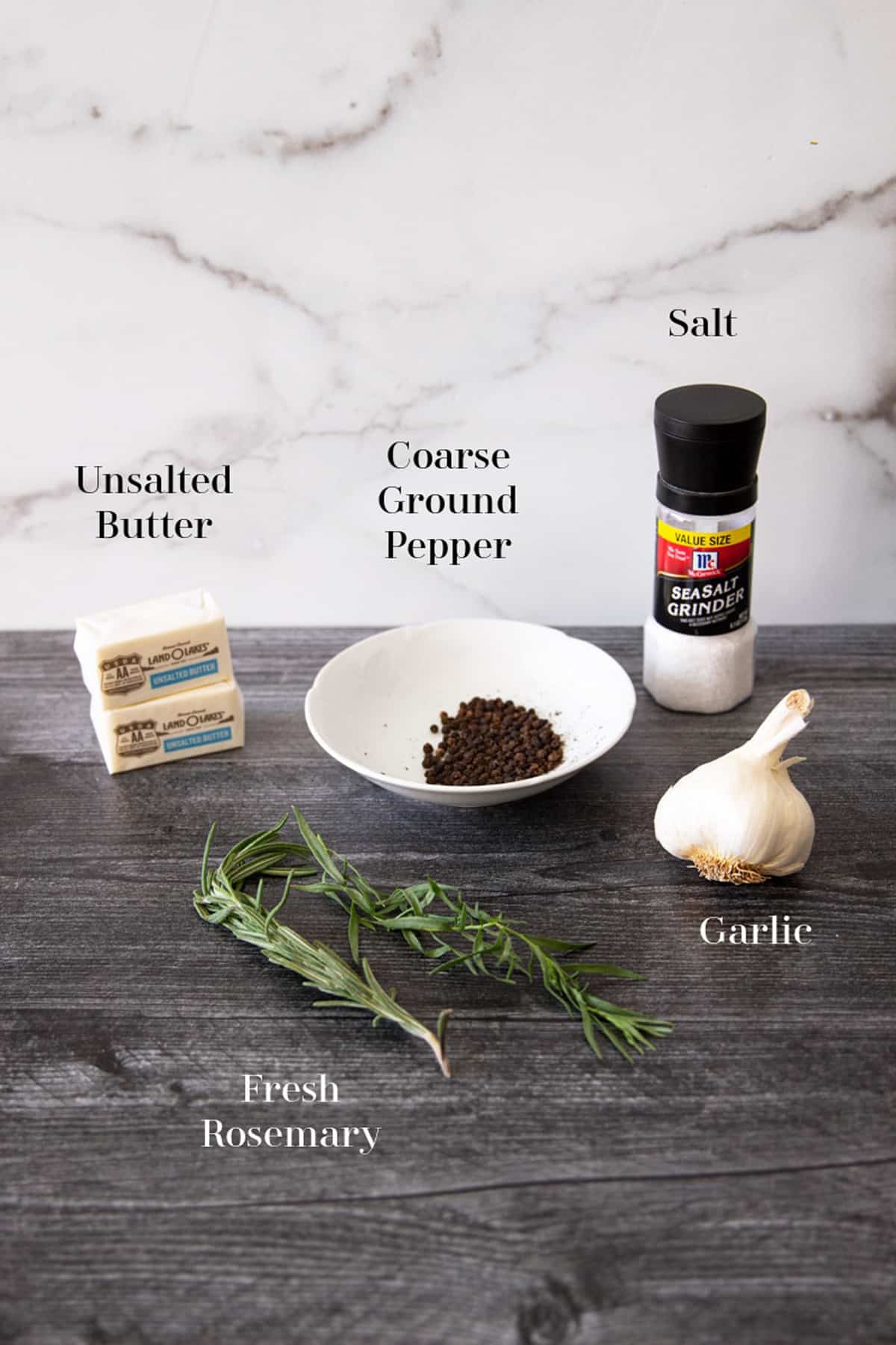 Butter, ground pepper, salt, garlic, and rosemary on counter.