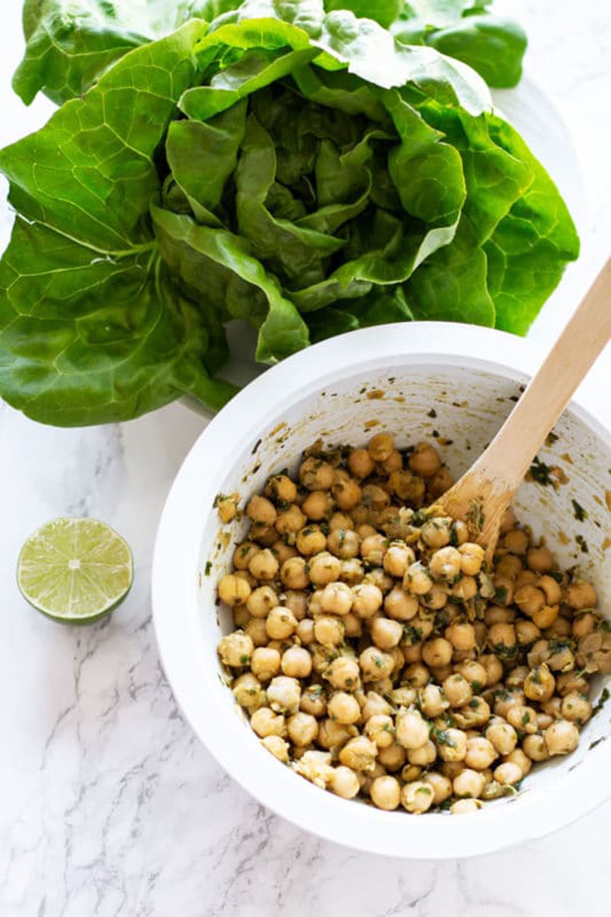 A bowl of seasoned chickpeas covered in basil pesto. 