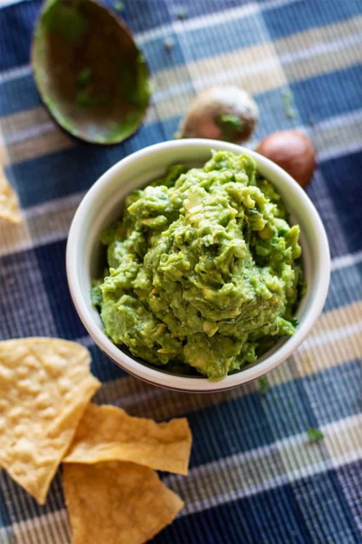 Bowl of guacamole being served with chips.