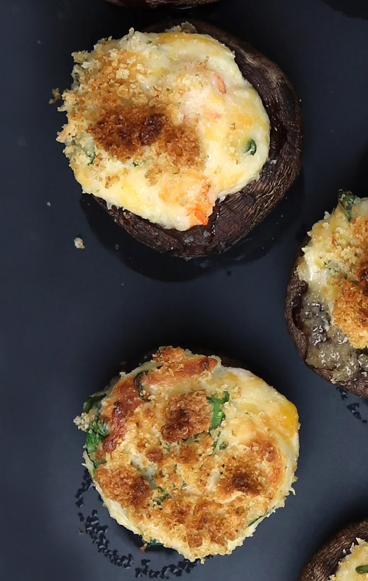 Stuffed mushroom caps filled with shrimp, cheese, spinach, and breadcrumbs.