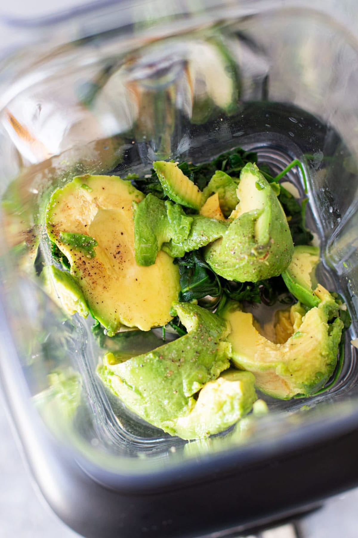 Close up of avocado, salt, pepper, and lemon juice in a blender.