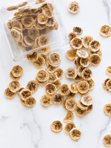 Banana chips spilled on the counter out of a container.