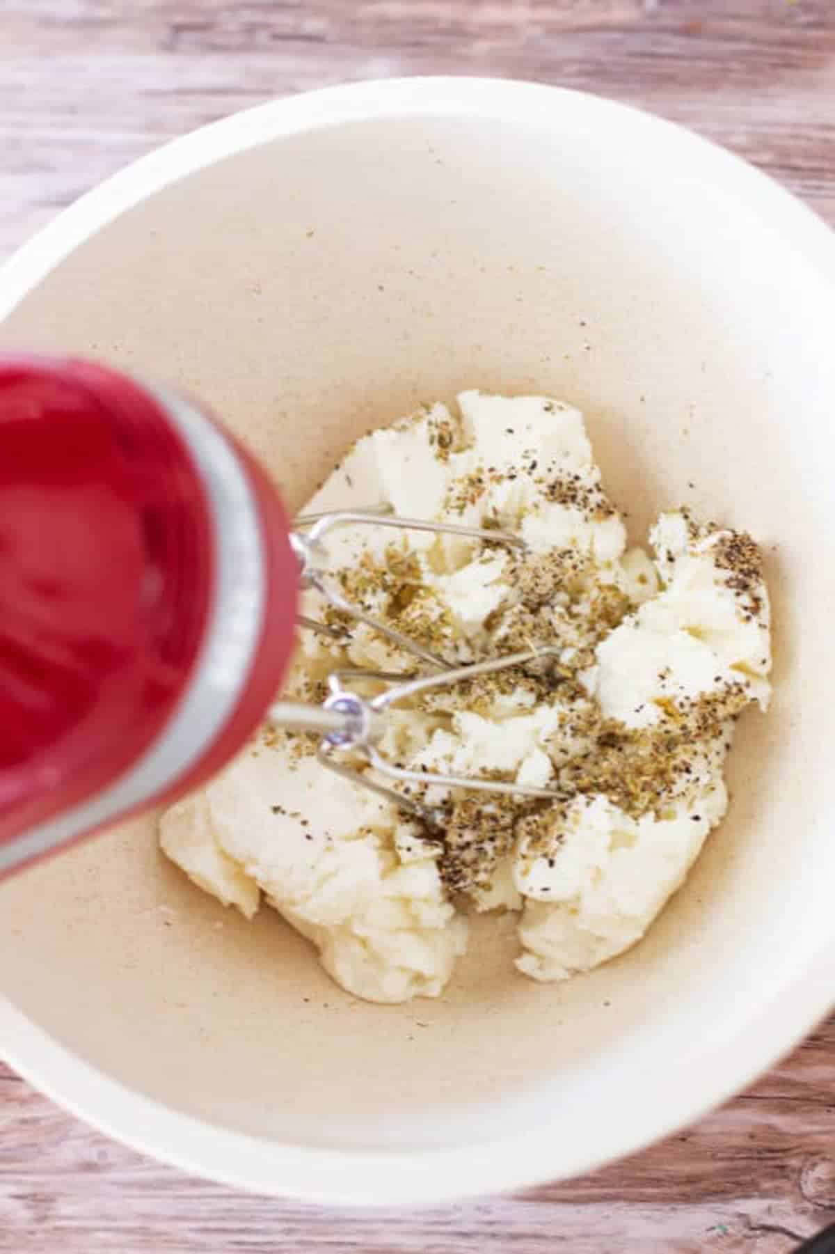 Person mixing together ricotta cheese with dried herbs. 