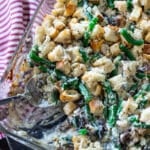 Person serving green bean casserole out of a casserole dish.