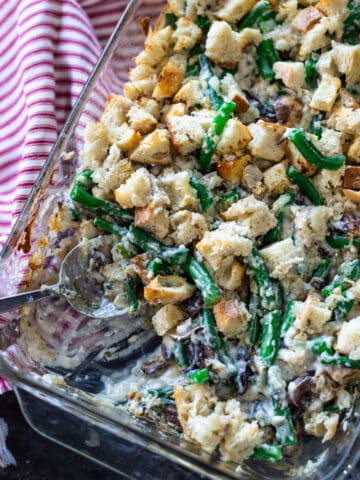 Person serving green bean casserole out of a casserole dish.