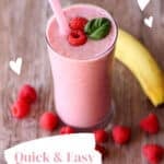 Glass filled with raspberry smoothie with bananas and raspberries on table.