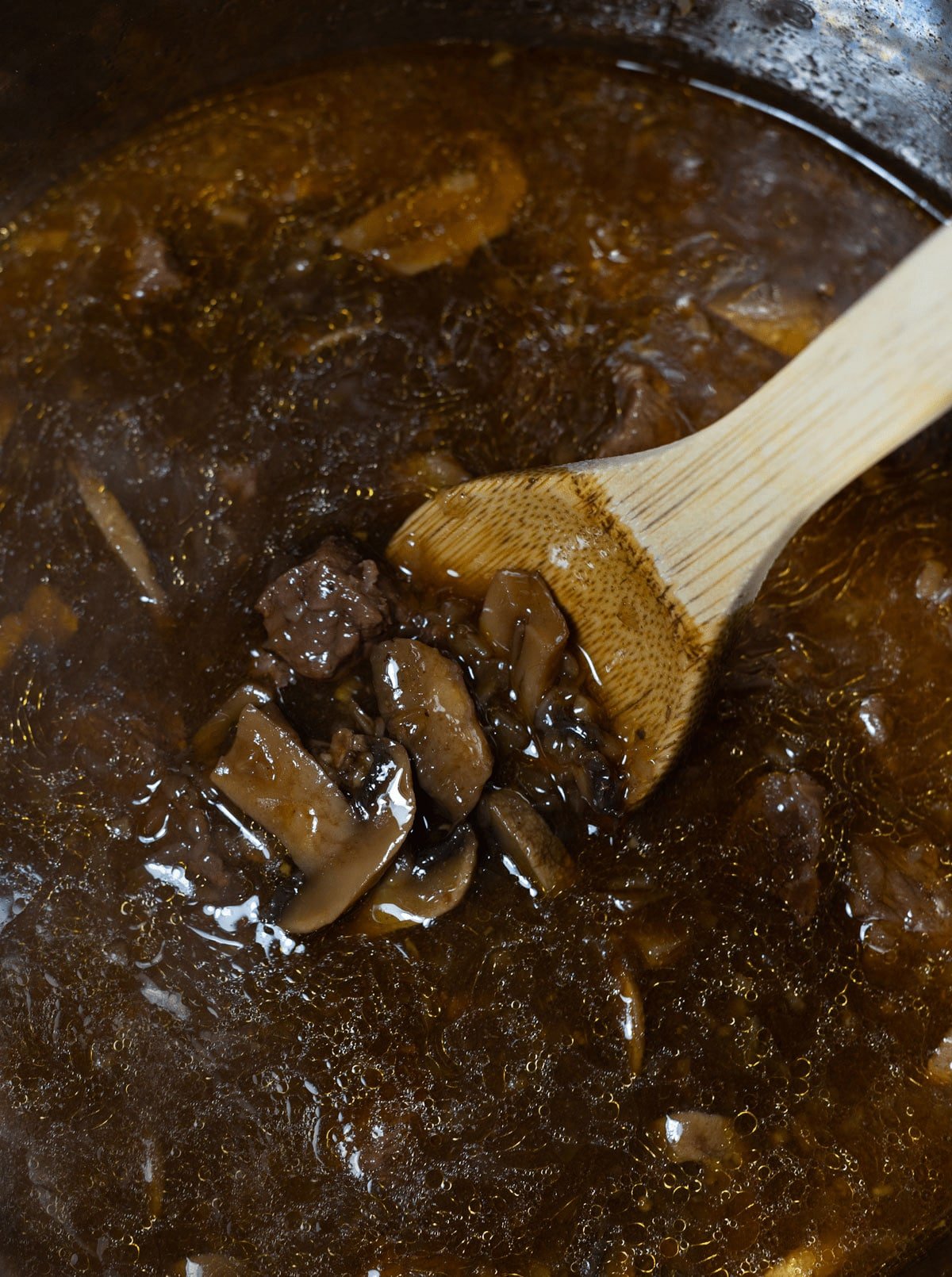 Person stirring Instant Pot Beef Tips. 