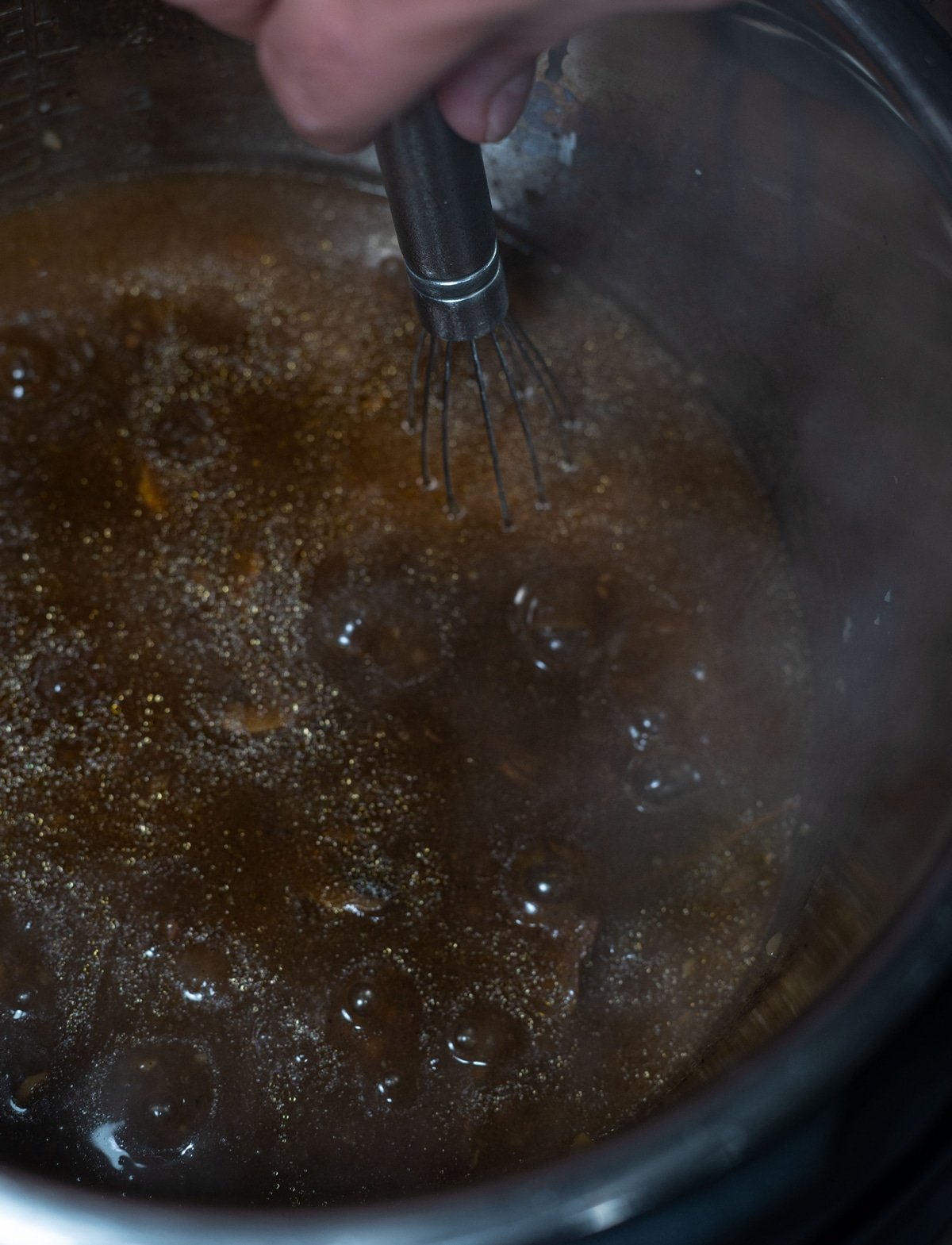 Person stirring beef broth for making beef tips. 