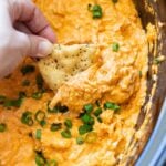 Chip being dipped into the chicken buffalo dip in a crock pot.