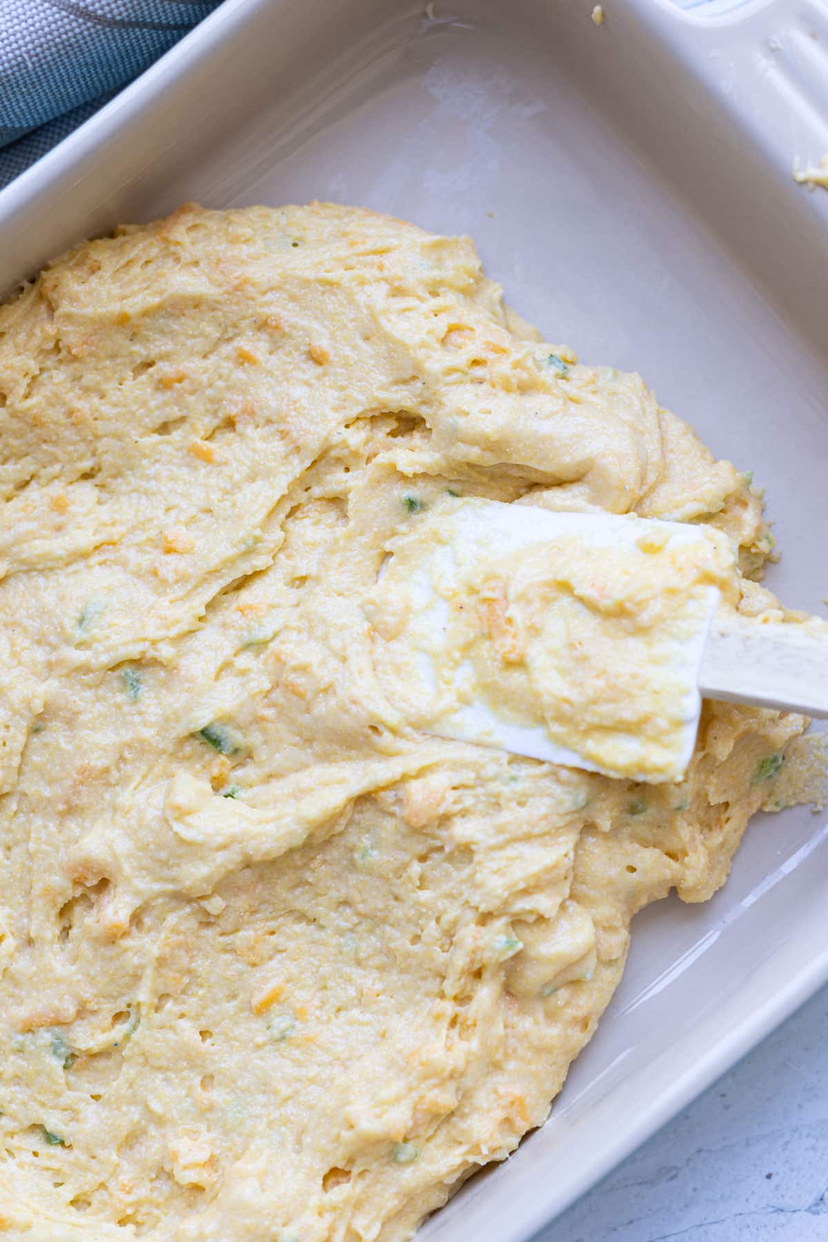 Person spreading cornbread mix in a baking dish. 