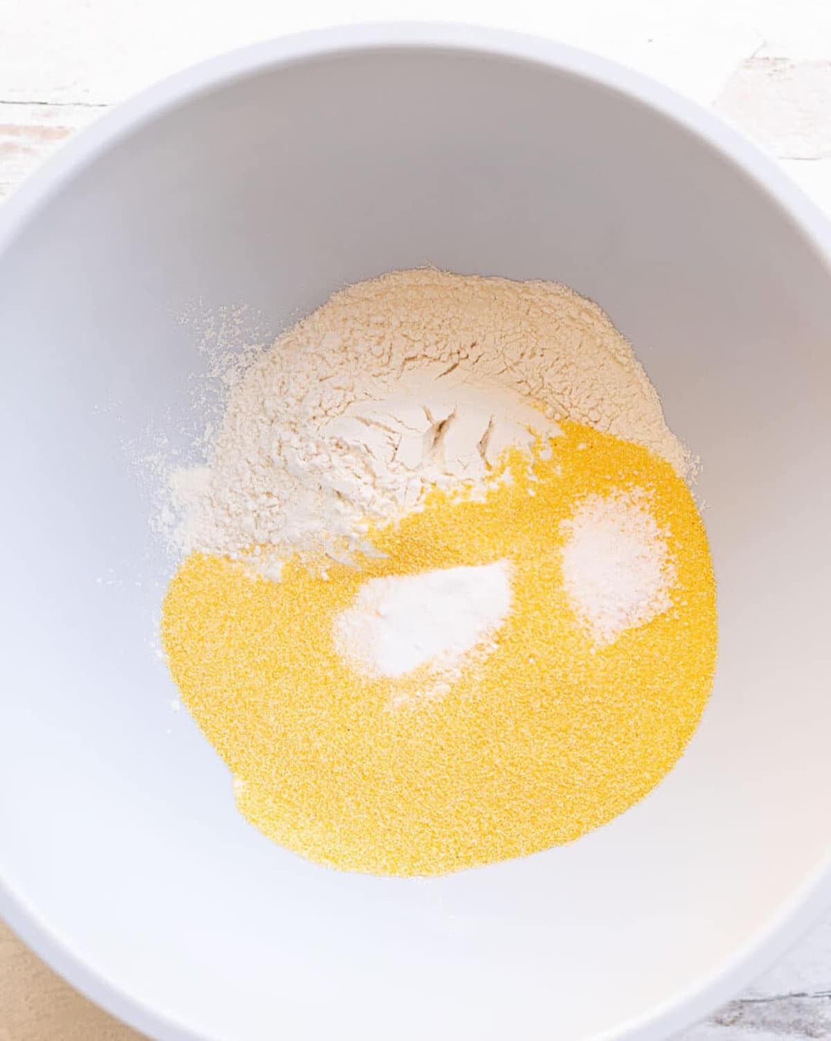 Large bowl filled with cornmeal, flour, salt, and baking soda. 