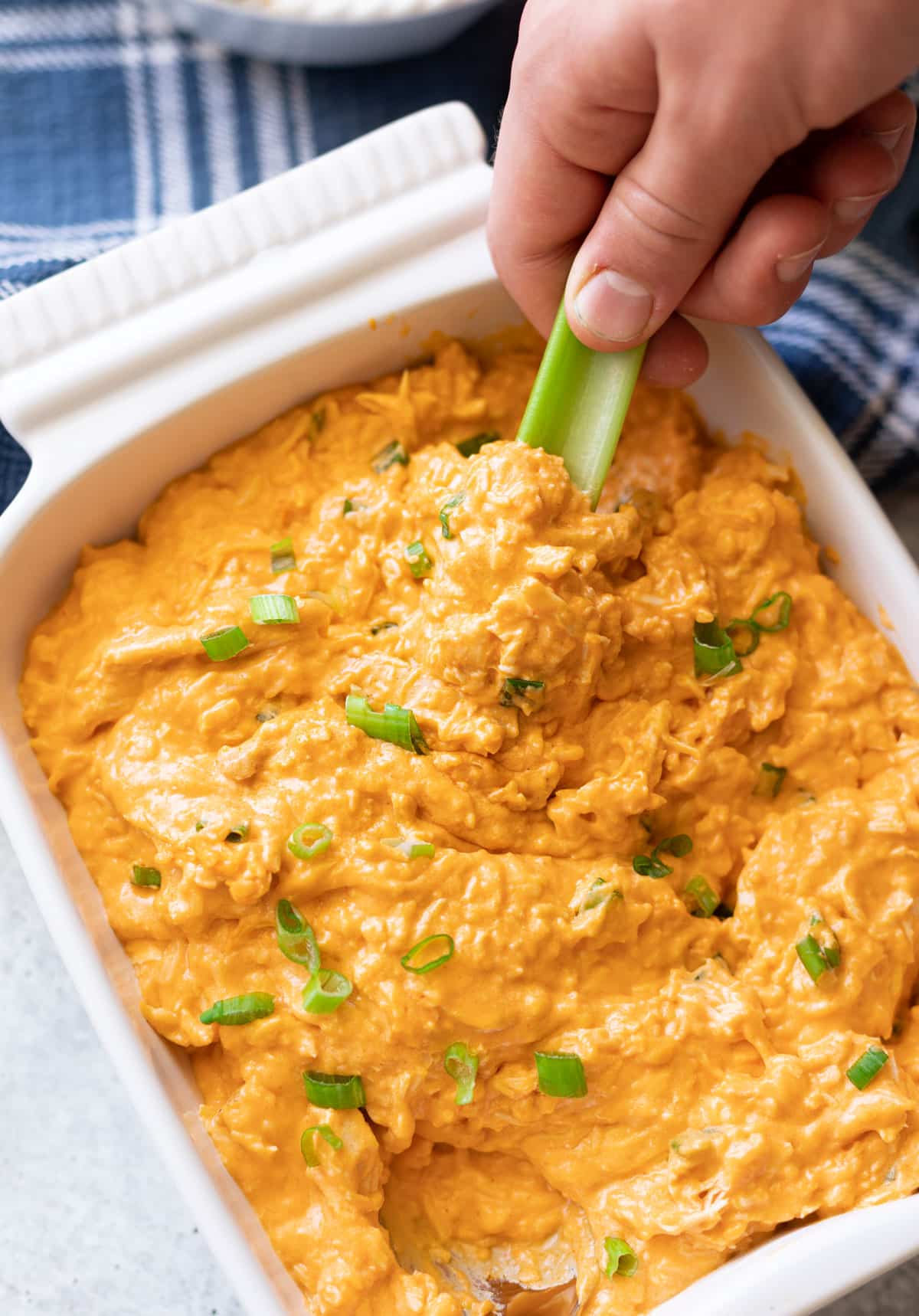 Person dipping celery in buffalo chicken dip. 