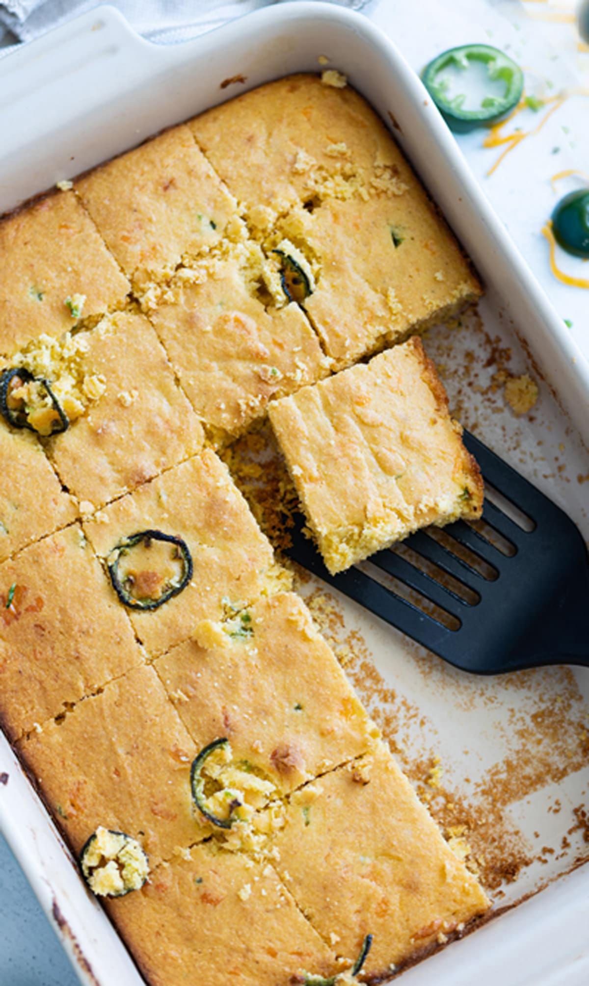 Person serving a piece of cornbread from a serving dish. 