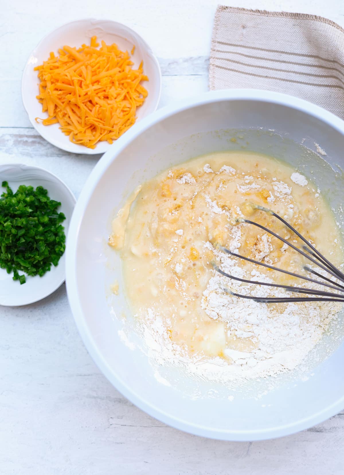 Large bowl filled with person mixing cornbread batter.