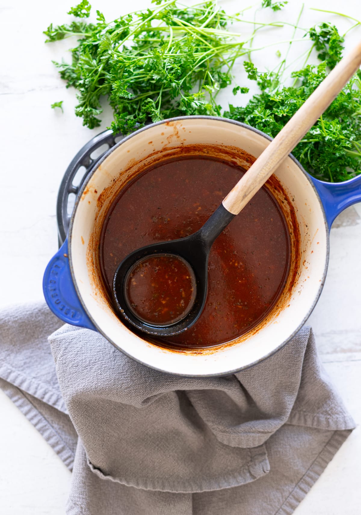 Person using a ladle to serve homemade enchilada sauce.
