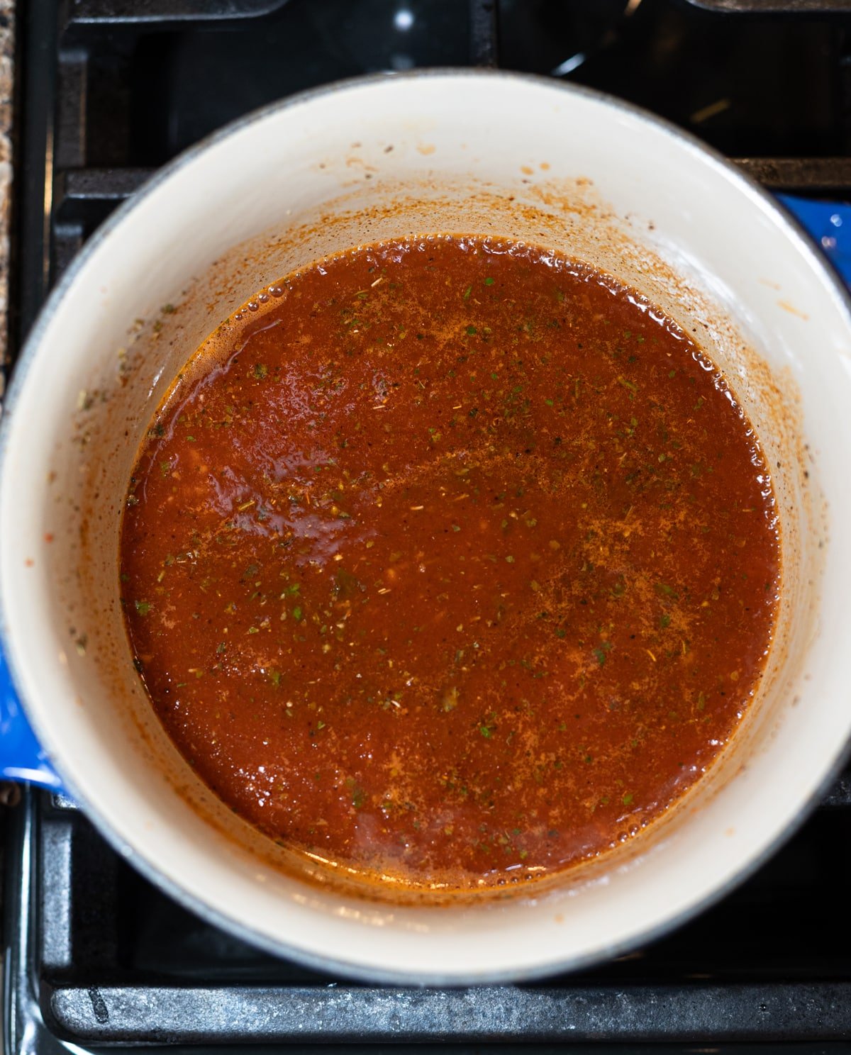 Enchilada sauce cooking in a pan on the stove.