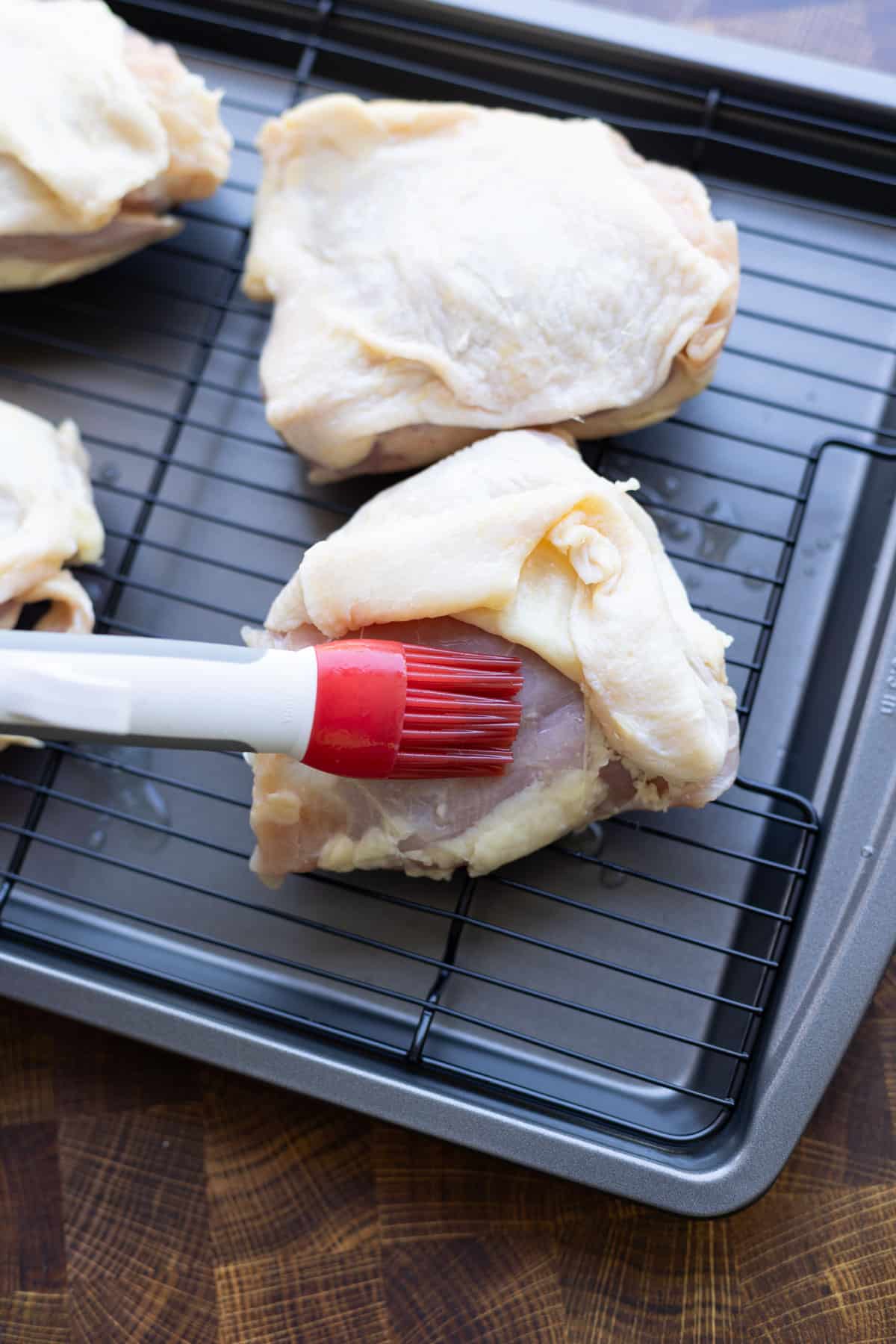 Person basting on melted butter onto a piece of chicken.